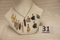 Display of 12 different natural stone pendants arrayed on bust with silver chain
