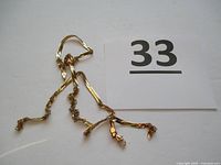 Full view of twisted and broken gold chain with clasp