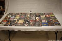 Wide view of 50 hard metal rock music CDs laid out on table in several rows.