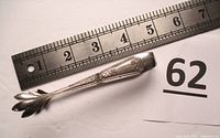Sugar tongs placed under a ruler showing 4.5 inch length.