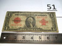 Front view of 1923 Series one dollar bill showing red seal and serial number with visible creases and wear.