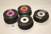 Stacks of vintage 7-inch vinyl 45 RPM records with colored center labels in various stacks.