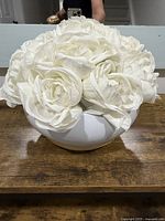 Full view of artificial white rose bouquet in ceramic bowl on wooden surface