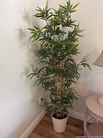Full view of artificial tree standing in corner inside white pot
