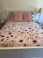 Full queen bed with floral duvet cover, two matching shams, two pink throw pillows