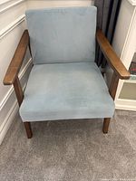 Front view of light blue upholstered chair with wooden arms and legs