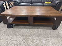 full view of coffee table front showing wood top, shelf, metal frame, wheels