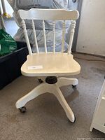 Full view of white wooden swivel desk chair showing spindle back, seat and base on casters