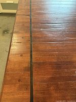 Close view of lane-strip wood tabletop with black seam and wear marks