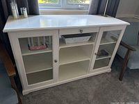 Front view showing entire white IKEA sideboard with glass doors, drawer and shelves