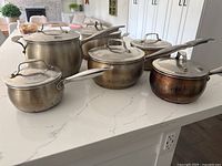 Six Lagostina stainless pots and saucepans with lids on countertop