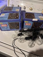 Three boxed Old Time Pottery Solar LED Edison String Lights with one loose strand