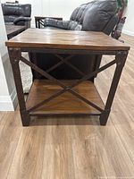 Front angle view of one end table showing wood top, metal legs, X-brace, lower shelf