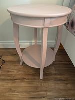 Overall view of round pink side table with lower shelf