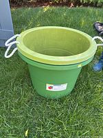 Full view of one green 67 L rope-handle tote standing on grass