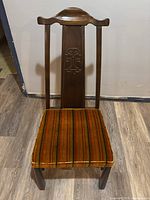 Front view of a vintage Chinese yolk back wooden dining chair with orange striped velvet seat upholstery.