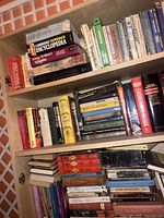Bookshelf full of diverse vintage books including Cambridge Paperback Encyclopedia, King Arthur's Knights, and other novels and references.