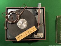 Front view of the Garrard turntable showing wood-style base, tonearm, platter, and large record spindle in box on platter