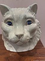 Front view showing detailed cat face with blue eyes and sculpted fur.