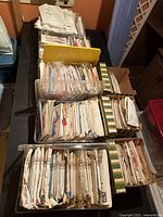 Top down image of eight boxes filled with vintage sewing patterns, envelopes mostly intact but worn.