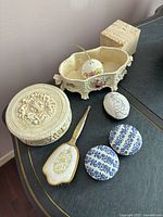 Overview photo showing all dishes including the large cream cherub dish, three smaller porcelain dishes with lids and silver enamel hairbrush.