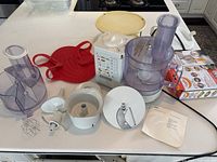 Overview of multiple kitchen items including Braun machine parts and vintage kitchen tools on a white counter.