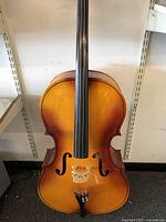 Front view of Engelhardt wood cello showing light brown finish, fingerboard, tailpiece, bridge and strings.