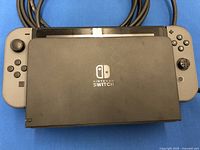 Top-down view showing the black Nintendo Switch dock with Nintendo Switch logo placed on top of the gray Nintendo Switch console with attached gray Joy-Cons.