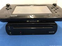 Nintendo Wii U GamePad on top of Wii U console showing front physical features and dual analog sticks on handheld