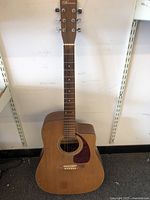 Front view of the full guitar showing the natural wood finish dreadnought cutaway body and fretboard.