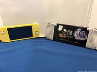 Yellow Nintendo Switch Lite and original Nintendo Switch consoles placed side by side on blue and white background.