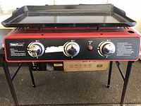 Front side of the red Royal Gourmet gas stove with three control knobs and removable griddle on top