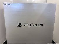White box showing Sony PS4 Pro branding on the front, box top flap open to reveal the console inside.