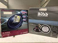 Photo of Pioneer TS-W304R and Boss CX122 subwoofers in original boxes showing brand names and key specs