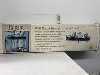 Box showing Madrid brand, product details and illustration of pot rack with hooks and mounted kitchen utensils.