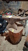 Front-left view of anvil seated on stump in basement setting