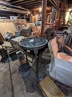 Full view of cast iron forge stand with bowl and coal, basement setting
