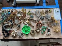 Overhead shot of all jewelry pieces on wood board under blue tape border