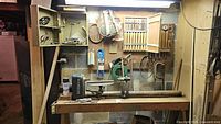 Wide view of the wood lathe with attached wall cabinet and lathe tools mounted on the wall above.