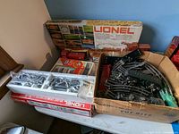 Overview of the Lionel Shifty Sam set including train cars in original packaging and a box full of track pieces and accessories.