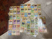 Assortment of loose and sleeved vintage Pokémon cards laid out on floor