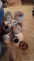 Multiple stoneware crocks and jugs arranged on floor with cake mold