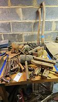 Full view of the lot showing woodworking tools including axes, vise, chisels, clamps, and files on a wooden table.