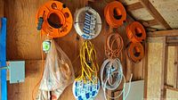 Wide view of garage wall with multiple cable reels, loose cords, and cable spools