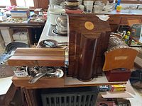 Photo showing four wooden boxes stacked together on a table surface with other kitchenware in background. Large carved box stands out with rounded front panel and circular inlay on the lid.