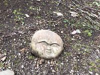 Front view of concrete moon face sculpture resting on ground