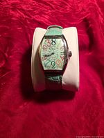 Front view of watch on pillow showing dial, strap and case