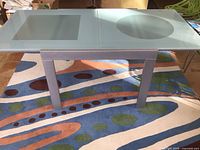 Table fully extended showing glass top with square and circle panels and base structure