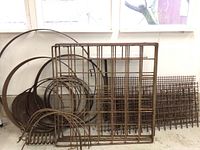 Overview of rusted steel rings, grid panel and woven sheets stacked against wall