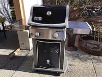 Full view of Weber Spirit grill with side shelves and closed cabinet